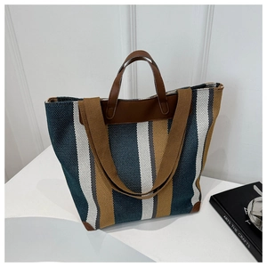 Detailed macro view of striped canvas tote bag with brown leather handles and reinforced corners