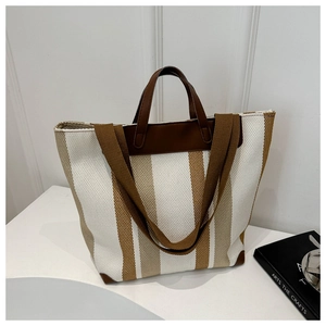 Detailed view of the striped canvas tote bag with brown leather trim and dual straps