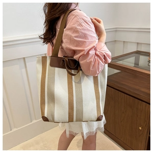 Close-up of striped canvas tote bag with brown leather trim and dual strap detailing