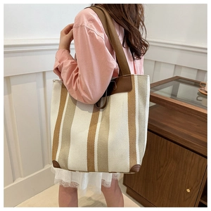 Detail of canvas tote bag with brown leather trim and stylish vertical stripes