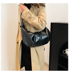 Detail of glossy black pleated shoulder bag showing premium faux leather texture and moon shape