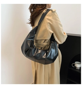 Detail of glossy pleated oversized hobo bag showing texture and black patent leather finish
