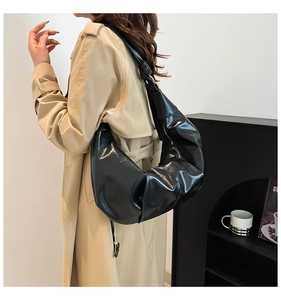 Detail of black pleated crescent bag featuring soft texture and fixed wide shoulder strap
