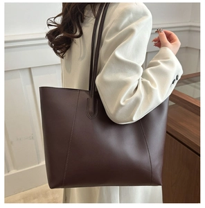 Detail shot of the smooth dark brown leather texture on a large capacity tote bag