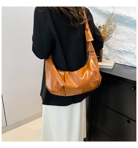 Detail of soft pleated texture on brown leather cloud shoulder bag with wide strap
