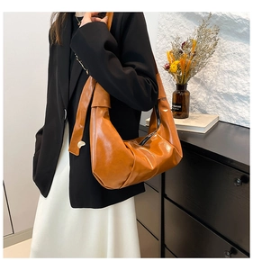 Close-up of caramel brown pleated shoulder bag showing glossy soft leather texture