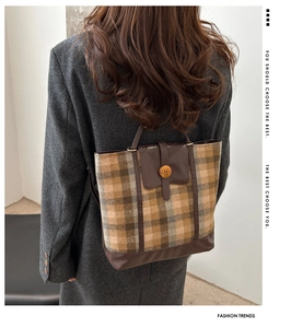 Detail of vintage plaid tote bag featuring brown leather trim and retro metal buckle