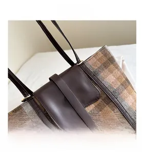Detail of plaid wool tote bag with leather strap and vintage gold metal letter N emblem