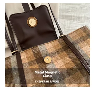 Close-up of golden magnetic hardware clasp on a brown plaid wool backpack detail