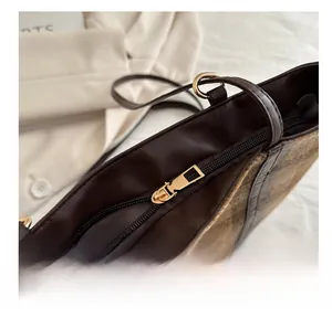 Detail of smooth gold metal zipper and brown leather trim on retro checkered tote bag