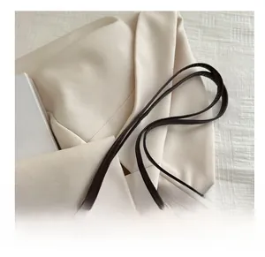 Detailed macro view of the dark brown leather handles and sturdy metal hardware of the bag