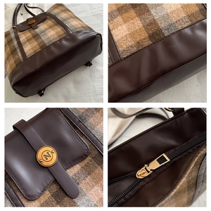 Detail of plaid tote bag featuring brown leather trim and golden metal N logo buckle