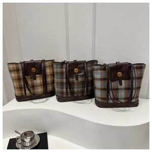 Detail of plaid tote bags with leather trim and decorative N buckle in retro British style