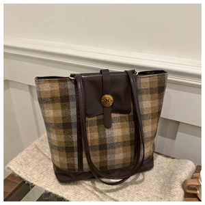 Close-up of a plaid tote bag featuring a gold N-letter buckle on tweed fabric