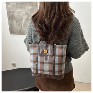 Detail of vintage plaid backpack with brown leather flap and round metal N buckle