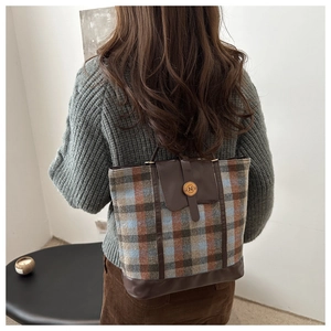 Detail of vintage plaid tote bag with leather trim and N logo shown on model