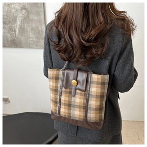 Detail of vintage plaid handbag featuring retro wool fabric and leather trim with N-button