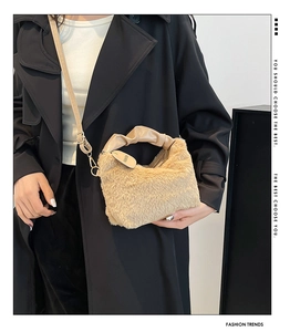 Detail of beige plush handbag featuring a pleated handle and adjustable crossbody strap