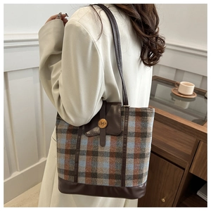 Detail of checkered tote bag featuring a leather strap and golden N-engraved buckle