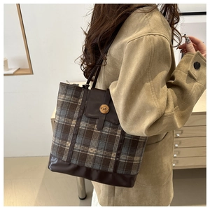 Detail of vintage plaid tote bag with brown leather trim and metallic N-letter buckle