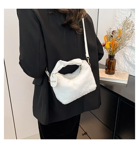Detail of white faux fur handbag with leather handle and fashion tag on dark clothing