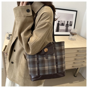 Detail of checkered plaid tote bag with brown leather trim and metallic N buckle