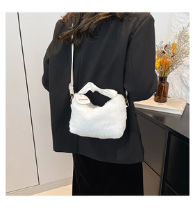 Detailed view of white plush faux fur shoulder bag with leather knotted handle and metal buckles