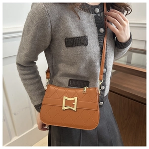 Sac bandoulière marron matelassé avec boucle dorée porté pour un style élégant et moderne