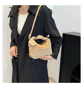 Close-up of beige plush handbag with ruched leather handle and fashion tag detail