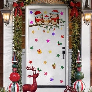 Detail of cute Christmas owl stickers on a white door with holiday wreaths and stars