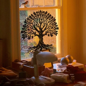 Dettaglio dell'adesivo silhouette Albero della Vita su vetro con controluce al tramonto