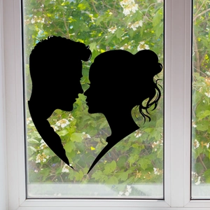 Dettaglio dell'adesivo per finestre con coppia silhouette nera su vetro e giardino