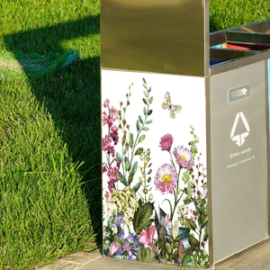 Outdoor stainless steel bin with floral vine pattern and 'Other waste' label on green lawn