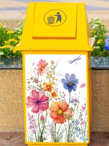 Close-up of colorful floral butterfly stickers on a yellow bin in a garden setting