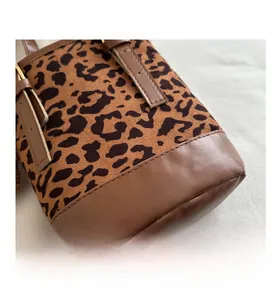 Detail of leopard print suede and brown faux leather handbag with logo lettering