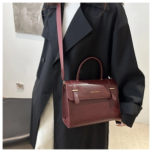 Détail du sac en cuir bordeaux avec logo doré et fermoir métallique brillant