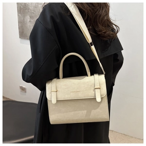 Détail du sac bandoulière beige minimaliste avec doubles sangles et texture mate et douce