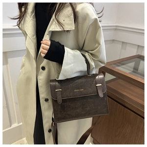 Détail du sac bandoulière vintage marron foncé avec texte mode et fermoir boucle en métal
