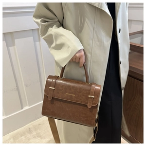 Détail d'un sac à main vintage en cuir PU marron avec lettrage doré et bandoulière