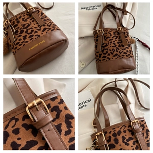 Detail of leopard print bucket bag featuring brown leather trim and golden hardware