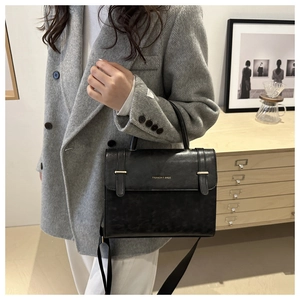 Détail du sac bandoulière vintage en cuir noir avec boucles dorées et logo mode