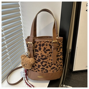 Detail of leopard print bucket bag with brown leather trim and plush bear charm
