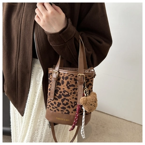Detail of leopard print bucket bag with plush bear charm and fashion logo text