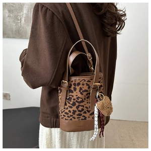 Detail of leopard print bucket bag featuring brown leather trim and cute bear charm