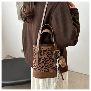 Detail of leopard print bucket bag with brown leather bottom and fashion text