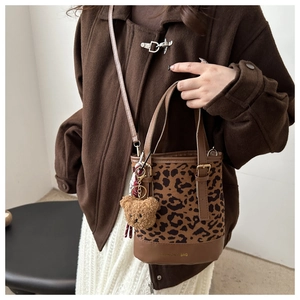 Close-up of leopard print suede bucket bag with brown handles and a cute bear charm