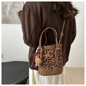 Close-up of leopard print bucket bag with suede texture and hanging plush charm detail