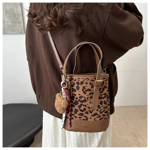 Detail of leopard print bucket bag featuring plush bear charm and fashion text logo