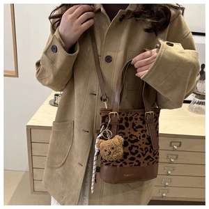 Lifestyle shot of model carrying a leopard print tote bag with brown plush bear charm