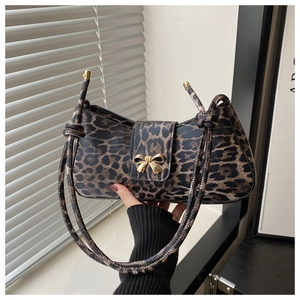 Detailansicht der Baguette-Tasche mit Leopardenmuster, goldener Schleife und dünnem Gurt